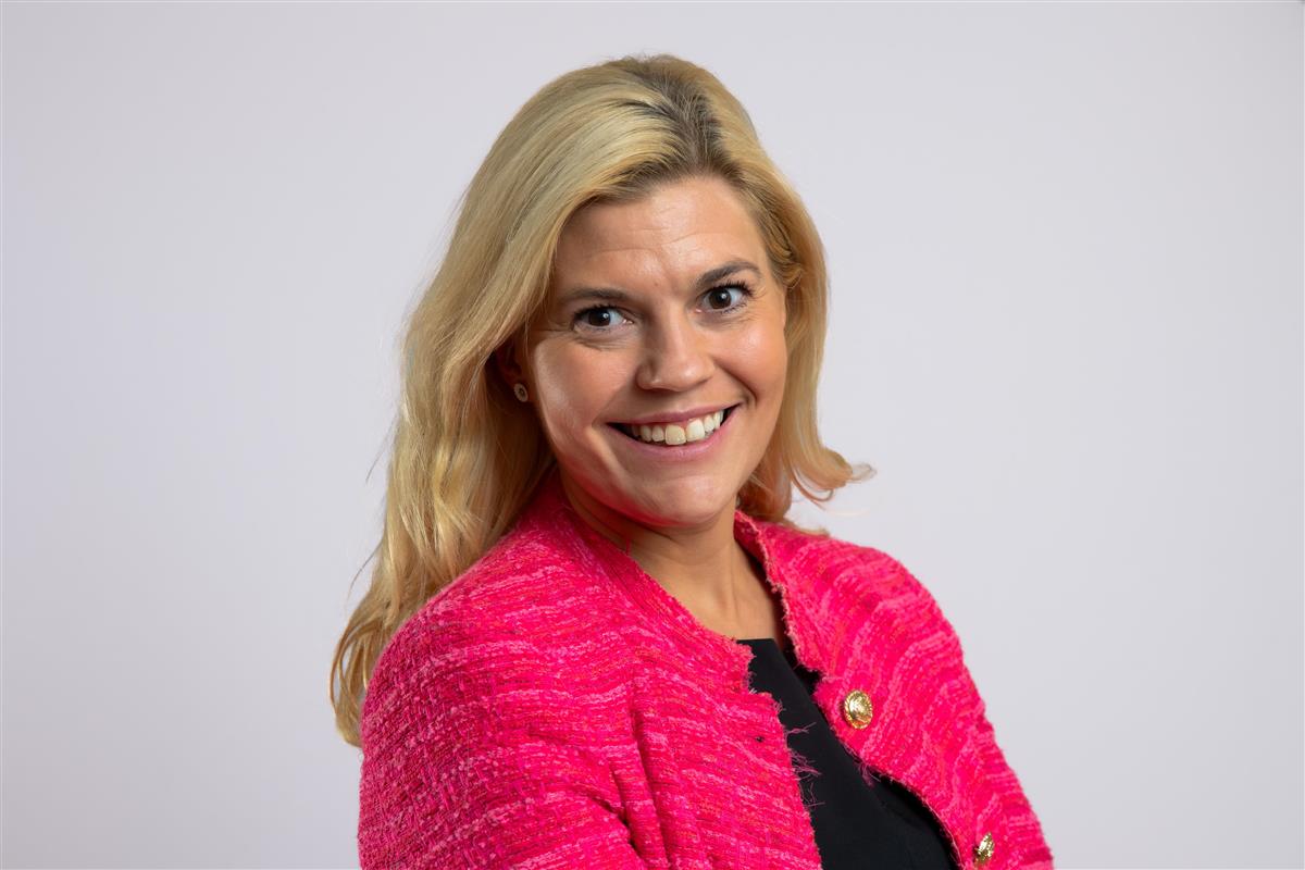 Portrettbilde av smilende kvinne med rosa jakke. - Klikk for stort bilde